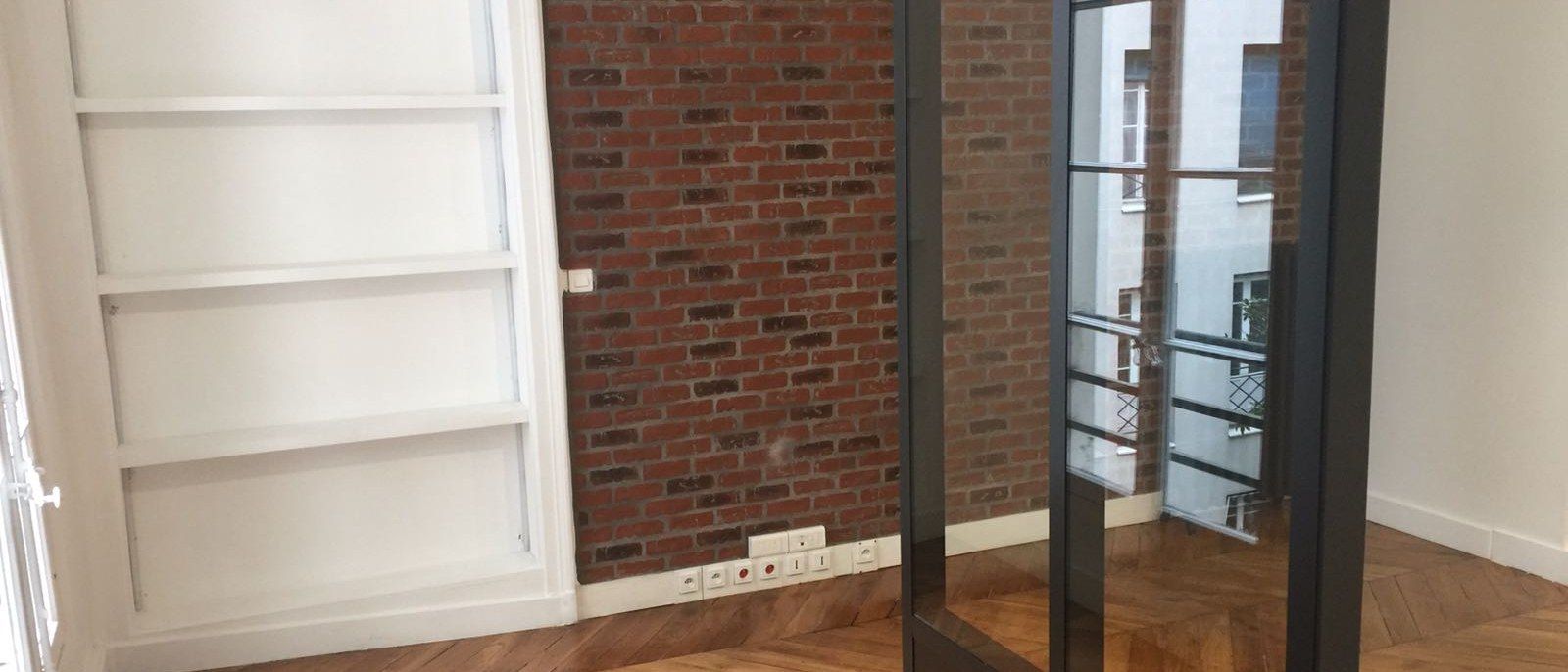 Verrière atelier et bibliothèque encastrée devant un mur de brique