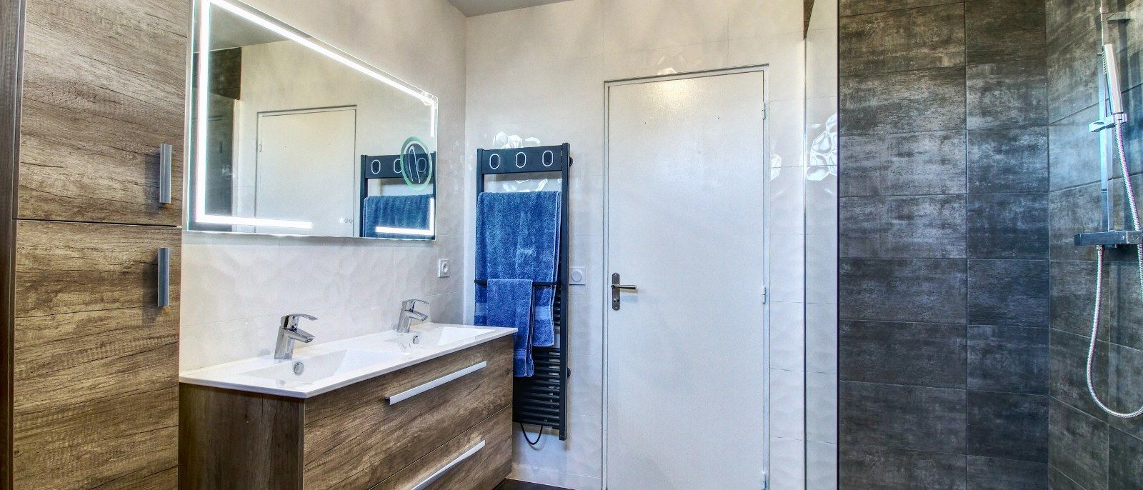 Salle de bain rénovée avec meuble vasque en bois et douche carrelée grand format