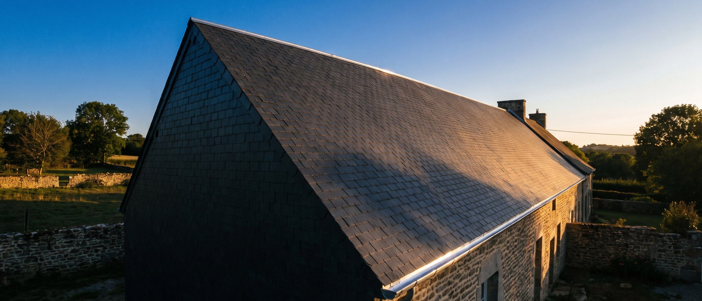 Longue pente de toiture refaite, éclairée par le soleil de fin de journée