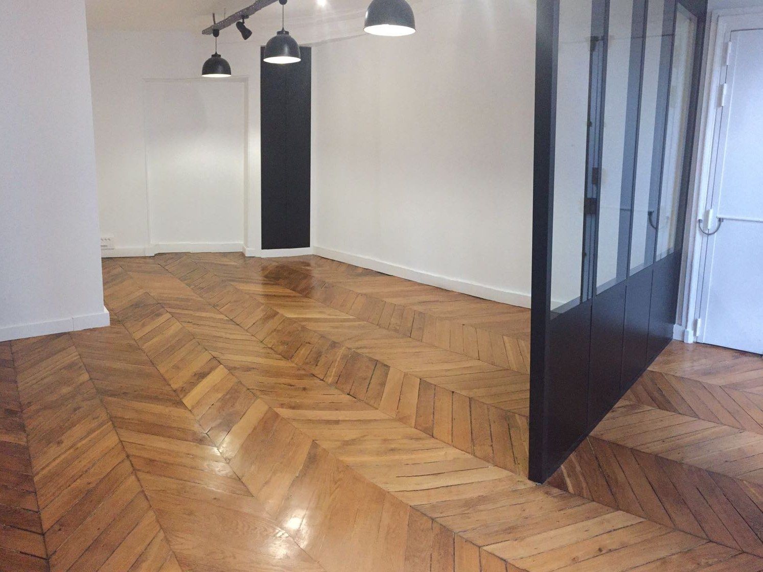 Pièce de vie rénovée : parquet chevron remis à nu et verrière acier séparant les espaces