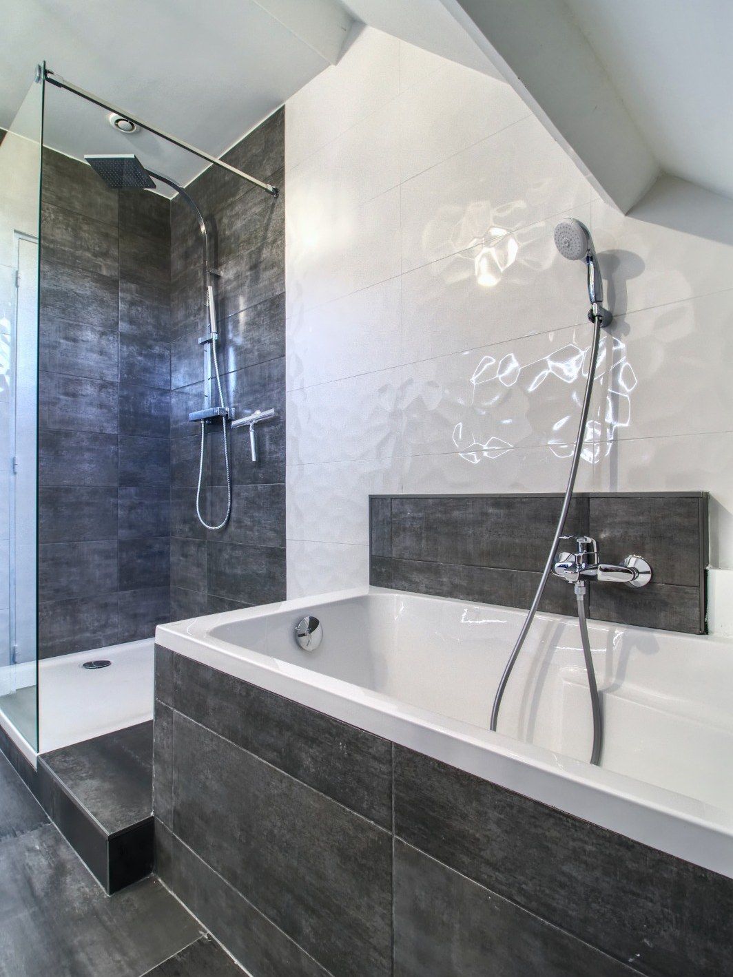 Salle de bain avec baignoire encastrée, carrelage anthracite et niche murale carrelée