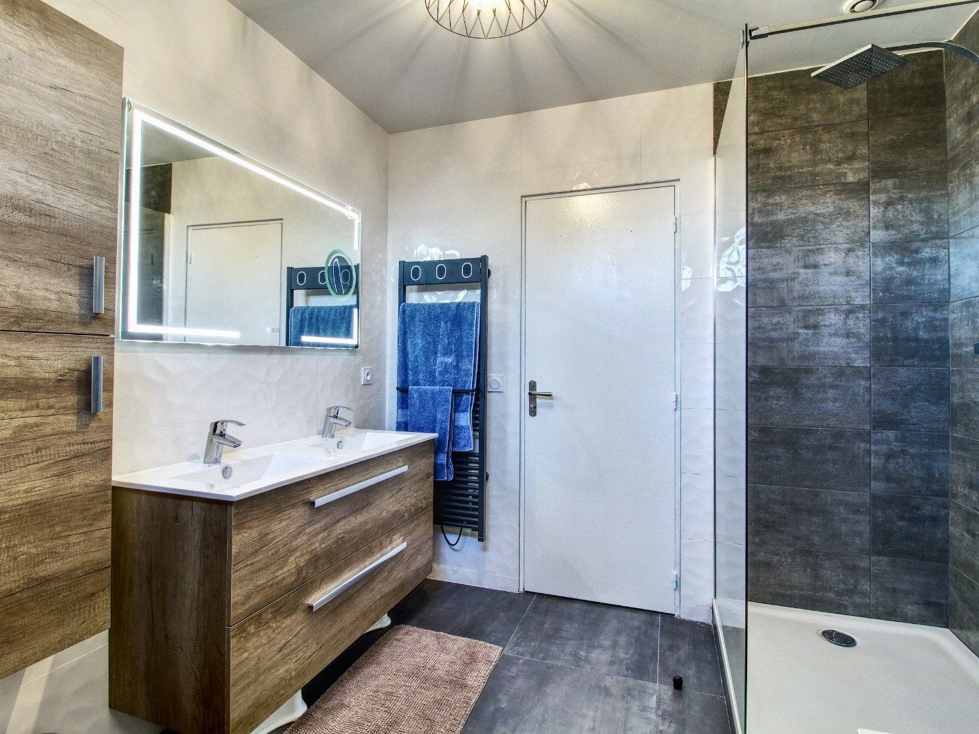 Salle de bain avec meuble double vasque en bois, miroir LED et douche à receveur extra-plat