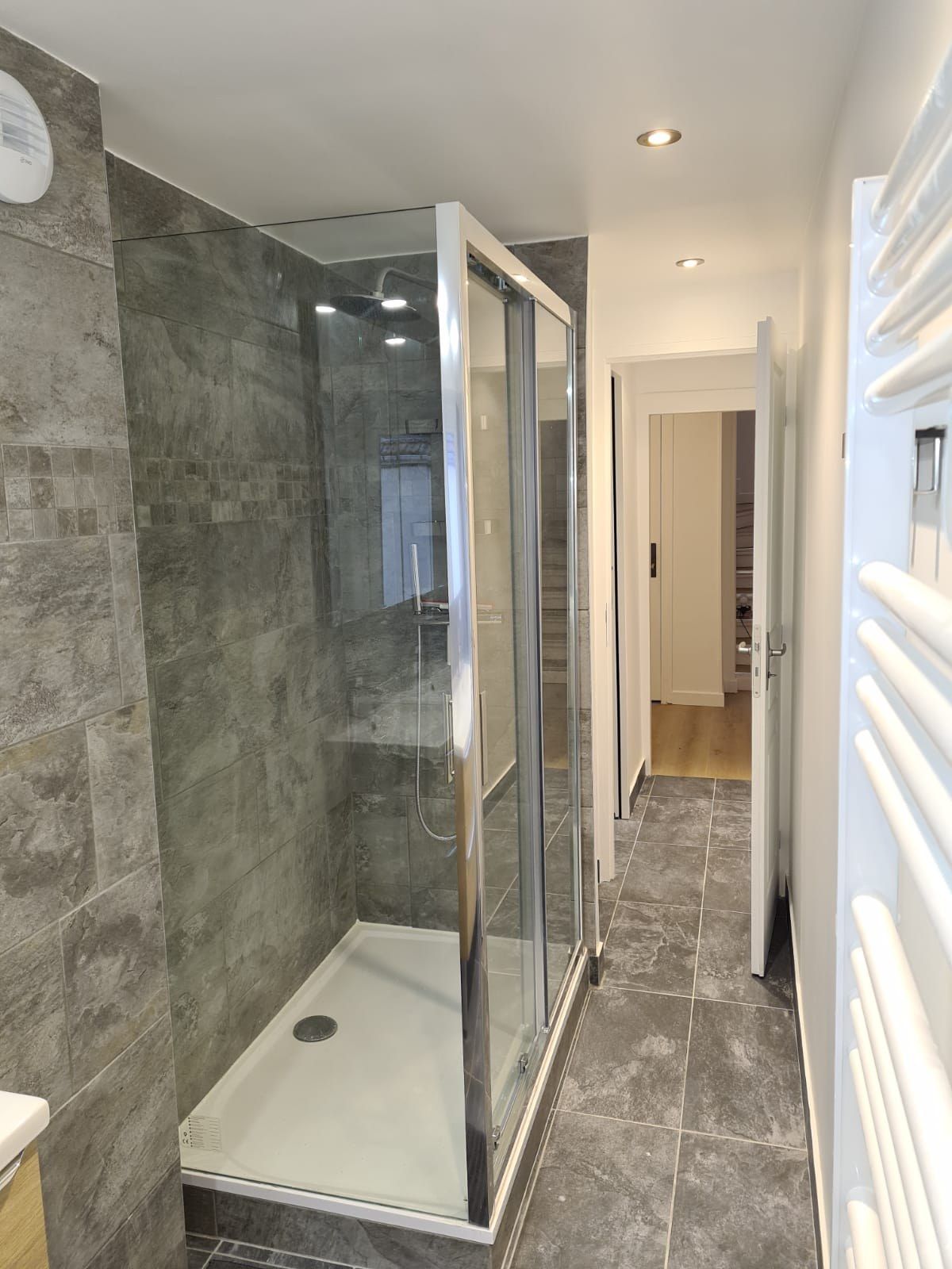 Salle d'eau avec douche à l'italienne, carrelage gris et paroi vitrée sur mesure