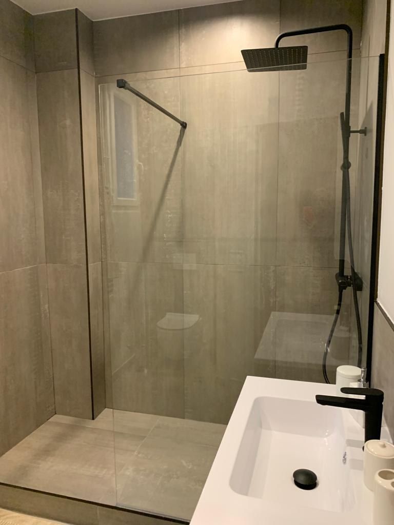 Douche à l'italienne avec receveur carrelé, robinetterie noire et vasque posée
