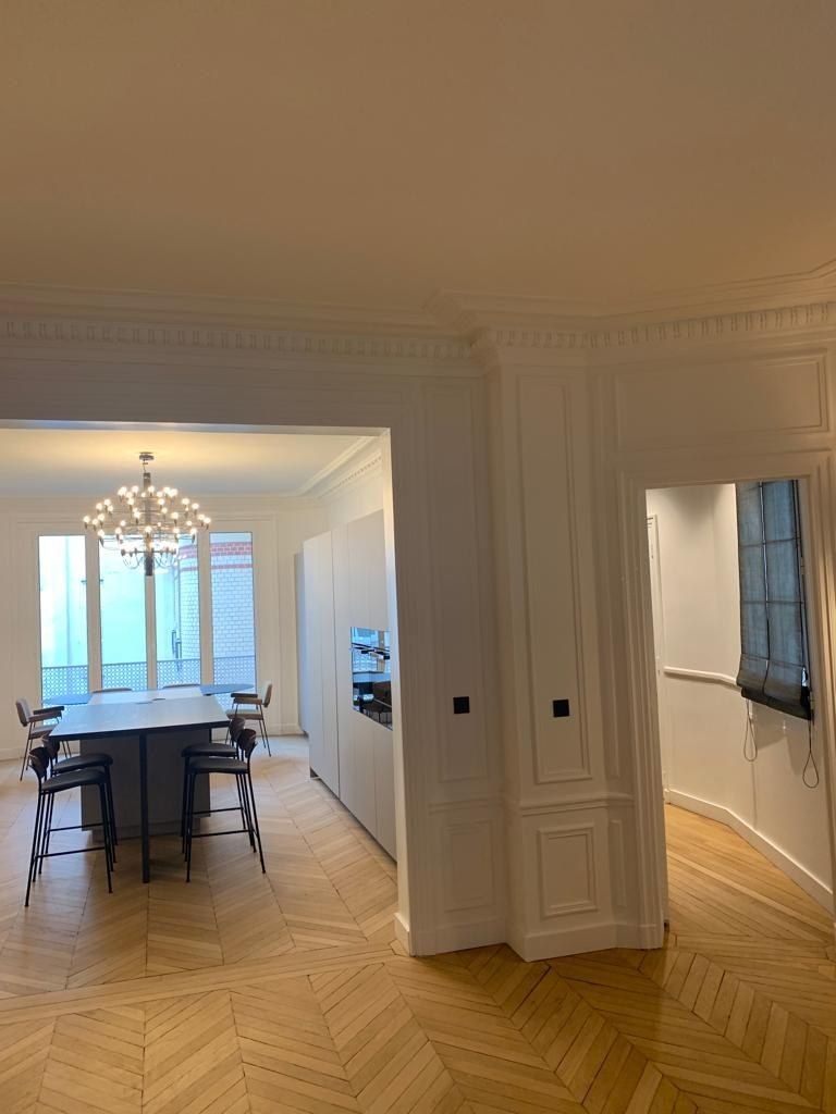Séjour d'appartement haussmannien rénové : moulures restaurées, parquet point de Hongrie et éclairage mural intégré