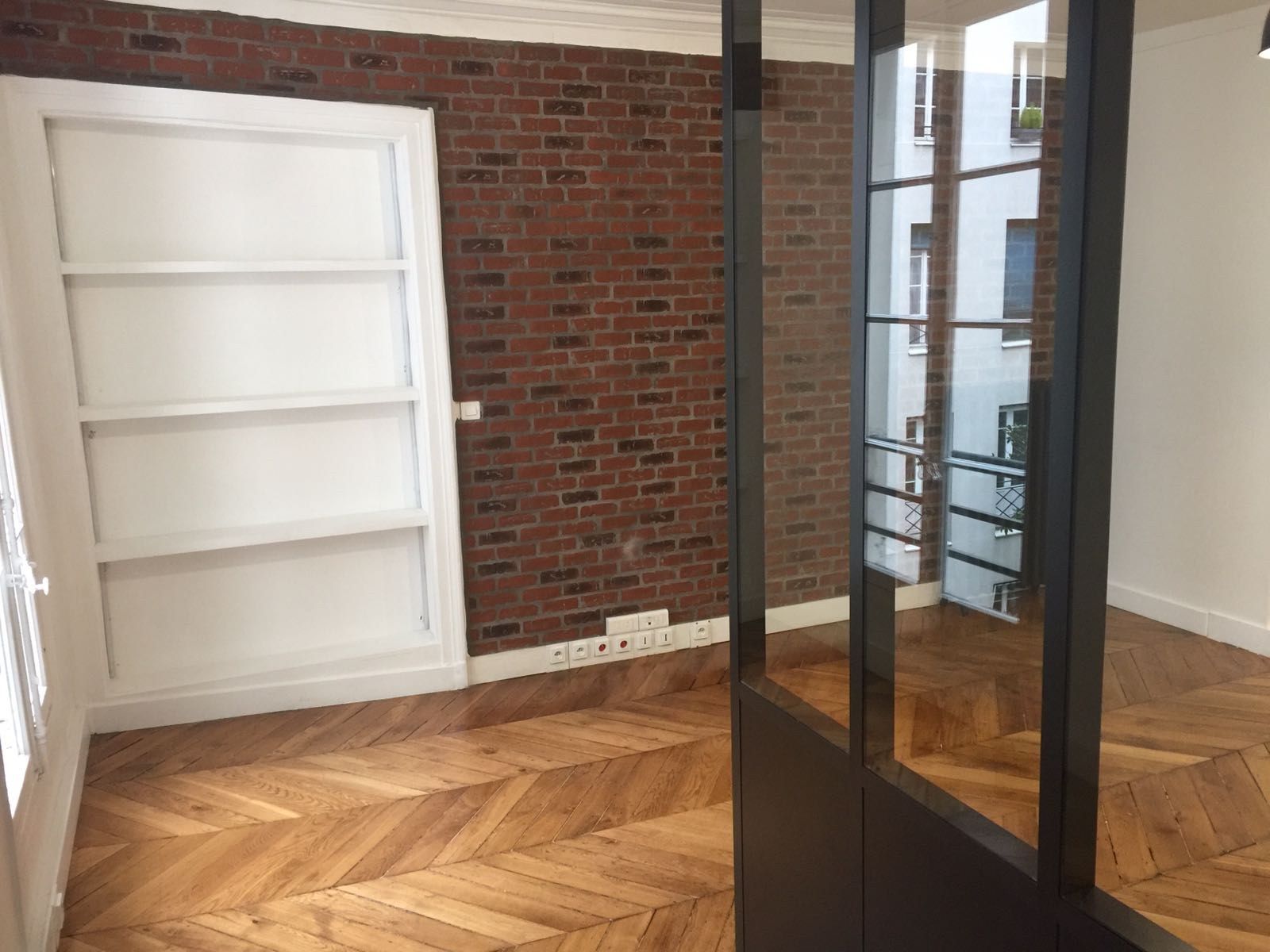Verrière atelier et bibliothèque encastrée devant un mur de brique conservé